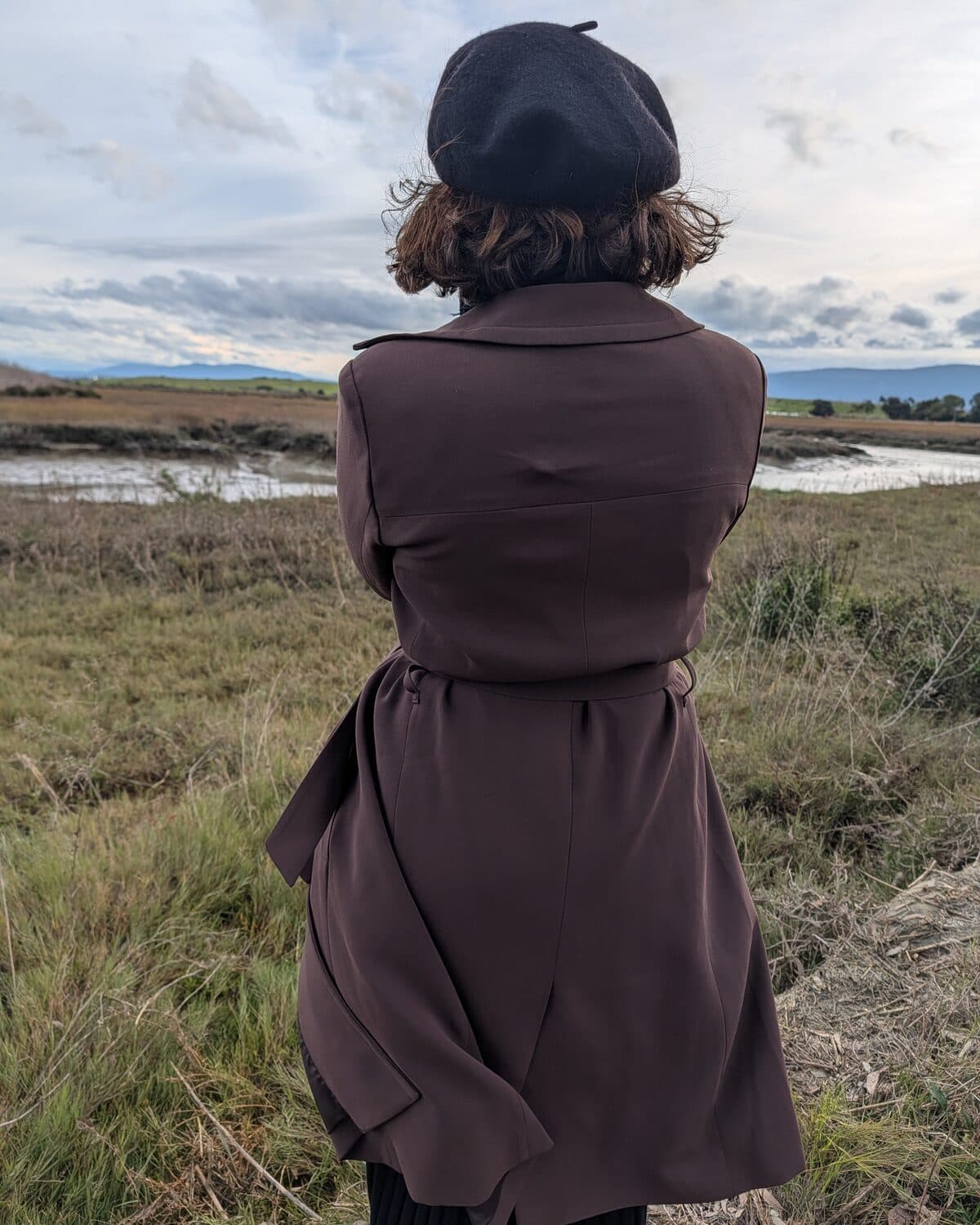 Anna, viewed from behind, looking out over a marsh landscape